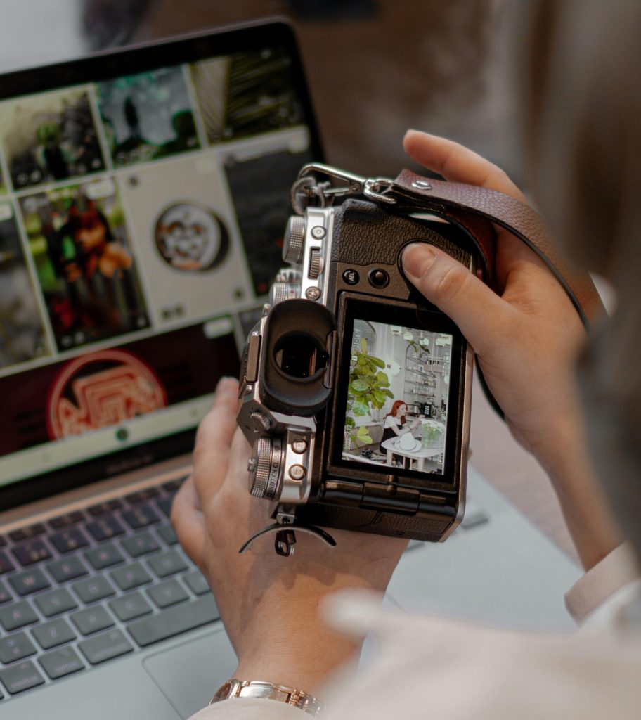 Close-up of a person using a digital camera and laptop for photo editing.